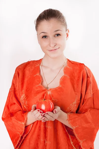 Girl in orange dress offers a red apple — Stock Photo, Image