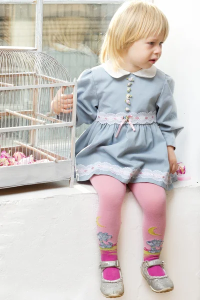 Маленькая девочка в платье сидит у окна с камерой — стоковое фото