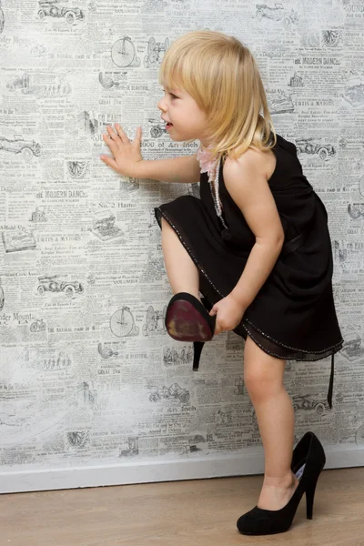 Das kleine Mädchen misst die Schuhe der Mutter mit Absätzen — Stockfoto