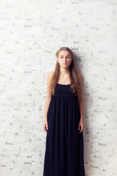 Gyönyörű lány, egy ruha, a fal mellett — Stock Fotó