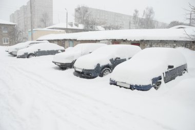 Parked cars covered with snow on the street clipart