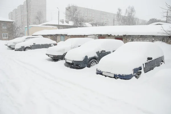 Припаркованные машины, покрытые снегом на улице — стоковое фото