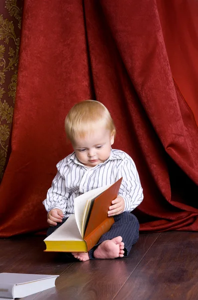 stock image Boy reading a book sitting on the floor against