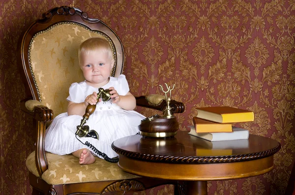 Menina com o telefone na mão sentado em uma cadeira velha — Fotografia de Stock