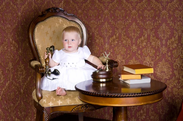 Flicka med telefonen i handen sitter på en gammal stol — Stockfoto