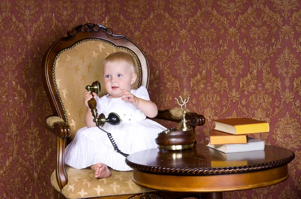 Menina com o telefone na mão sentado em uma cadeira velha — Fotografia de Stock