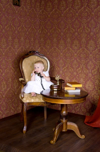 Κορίτσι με το τηλέφωνο στο χέρι του να κάθεται σε μια παλιά καρέκλα — Φωτογραφία Αρχείου