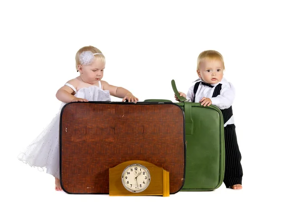 Niño y una chica vestidos como recién casados de pie cerca de equipaje —  Fotos de Stock