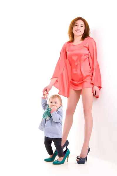 Matka drží ruku malou dceru, jak oblečení módní a nosila boty s podpatky — Stock fotografie
