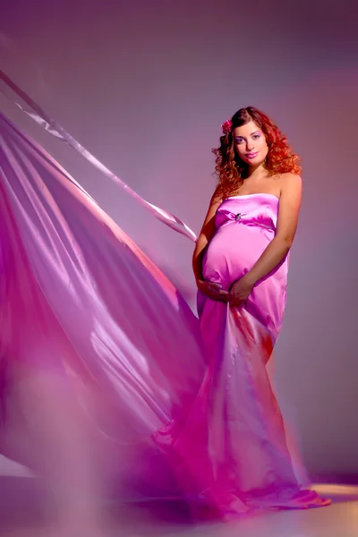 Mujer embarazada en una tela rosa volando —  Fotos de Stock