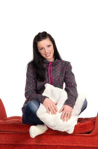 Девушка сидит на красном пуфе, обнимая белую подушку — стоковое фото