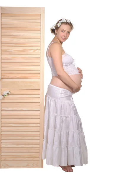 Hermosa mujer embarazada se encuentra cerca de una valla de madera — Foto de Stock