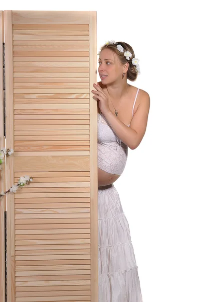 Красивая беременная женщина выглядывает из-за экрана — стоковое фото