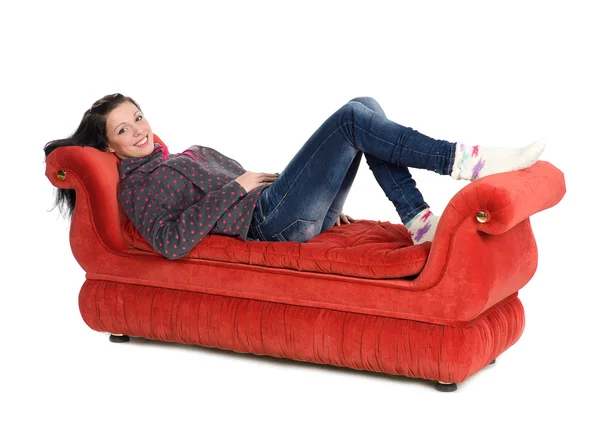 Beyaz arka plan üzerinde izole kırmızı kanepede yatan kız — Stok fotoğraf