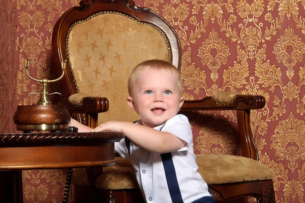 Criança em um terno sentado em um interior vintage com o telefone em seu — Fotografia de Stock