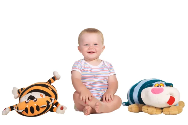 Criança sorridente sentada ao lado de um brinquedo macio — Fotografia de Stock