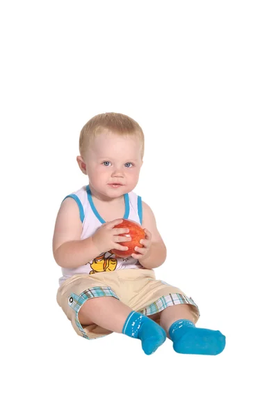Barnet sitter och håller ett äpple — Stockfoto