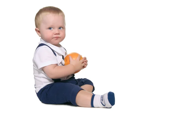 Baby sitting and holding an orange — Stock Photo, Image