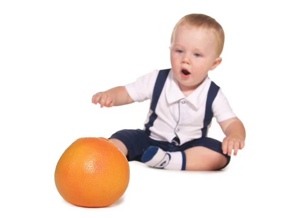 A criança estende-se à laranja, o foco em laranjas — Fotografia de Stock