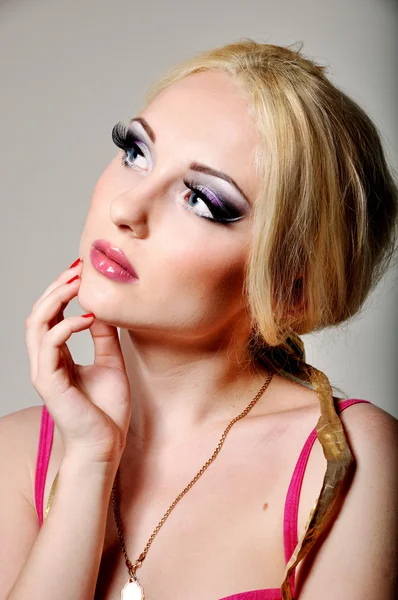 Блондинка з яскравим професійним макіяжем на сірому фоні — стокове фото