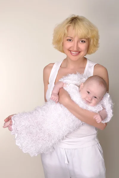 Una joven madre sonriente sostiene a su bebé en sus brazos — Foto de Stock