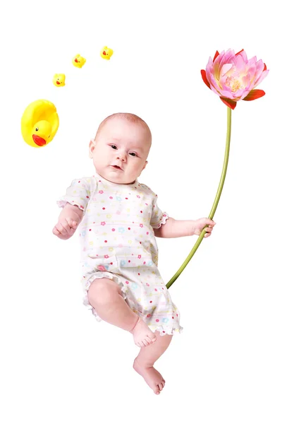 A baby with a big flower and some toy ducks — Stock Photo, Image