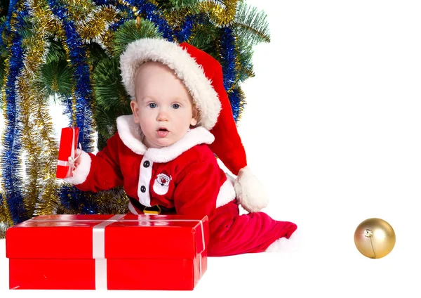 Menino vestindo o traje do Papai Noel sentado e segurando uma caixa com — Fotografia de Stock