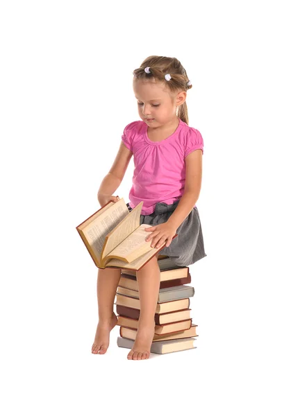 Jolie petite fille assise sur une pile de livres isolés sur du bac blanc — Photo