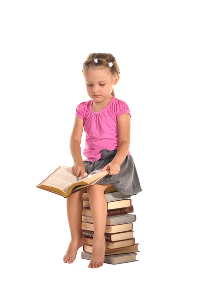 Nice little girl sitting on stack of books isolated on white bac — Stock Photo, Image
