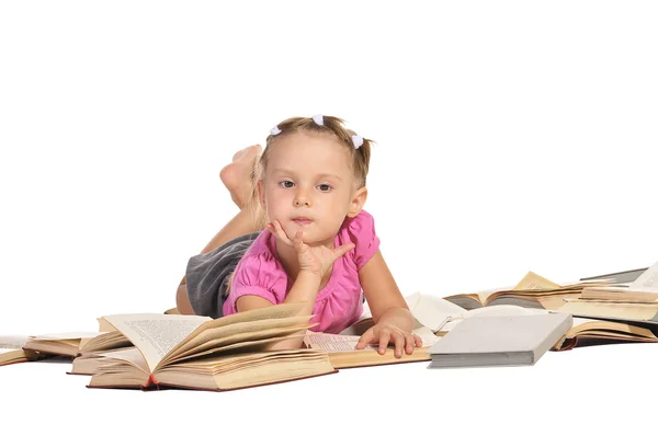 Nice little girl lying on pile of books isolated on white backgr — Stock Photo, Image
