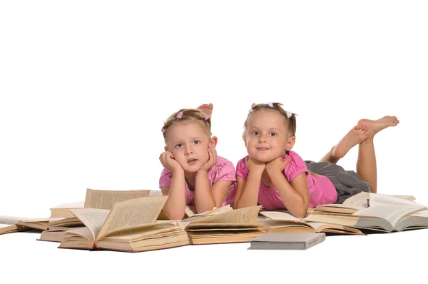 Zwei nette kleine Mädchen, die auf einem Stapel Bücher liegen, isoliert auf weißem Ba — Stockfoto