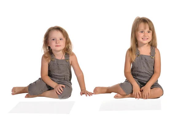 Twins sisters in rompers sitting isolated on white background — Stock Photo, Image