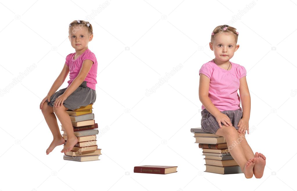Two nice little girls sitting on stack of books isolated on whit