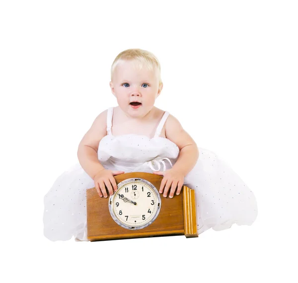 Дівчина в білій сукні сидить біля старого годинника — стокове фото