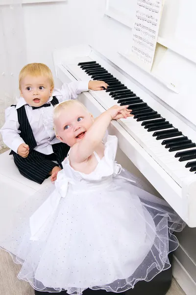 Мальчик и девочка играют на белом пианино — стоковое фото