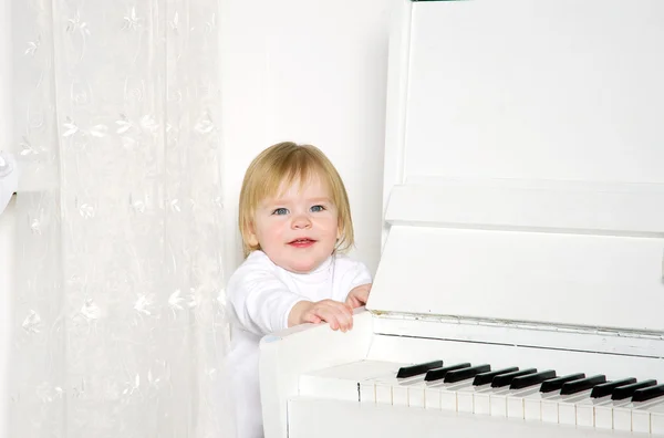 Dziewczyna siedzi obok biały fortepian — Zdjęcie stockowe