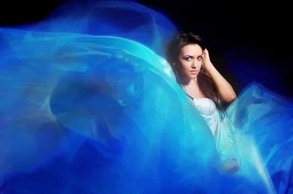 Meisje in de blauwe jurk van vliegen stof — Stockfoto