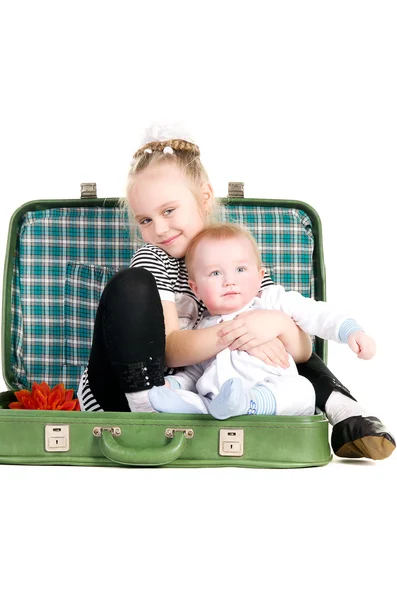 Αδελφή αγκάλιασμα αδελφός, κάθεται σε μια παλαιά βαλίτσα πράσινο — Φωτογραφία Αρχείου