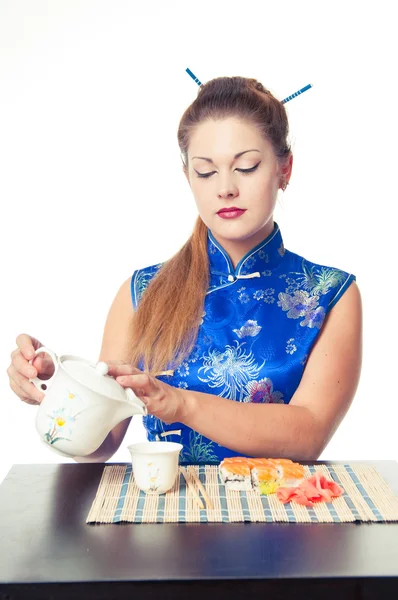 Girl pouring tea and eating sushi — Stock Photo, Image