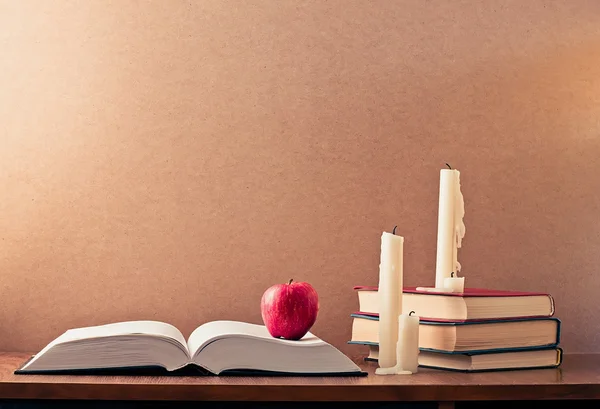Книга, красное яблоко и три свечи — стоковое фото