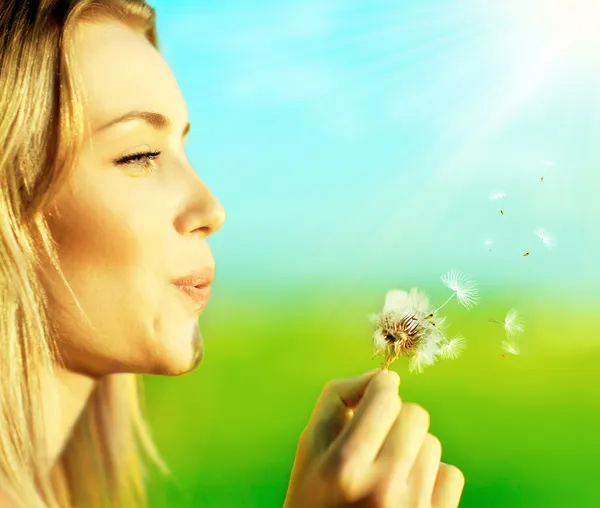 Happy beautiful girl blowing dandelion — Stock Photo, Image