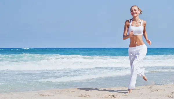 Gesunde Frau läuft am Strand lizenzfreie Stockbilder