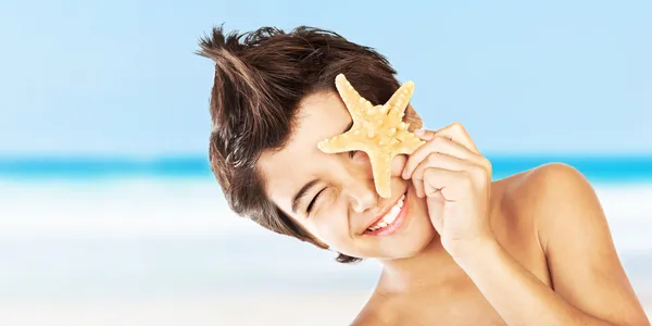 ビーチでヒトデと幸せそうな顔の少年 — ストック写真