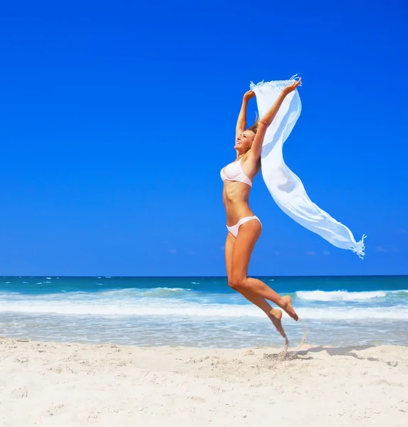 Skákání šťastná dívka na pláži — Stock fotografie