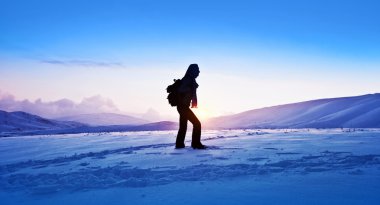 Woman traveler hiking in winter mountains clipart