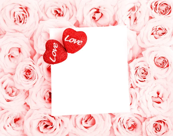 Красиві рожеві троянди з подарунковою карткою та сердечками — стокове фото