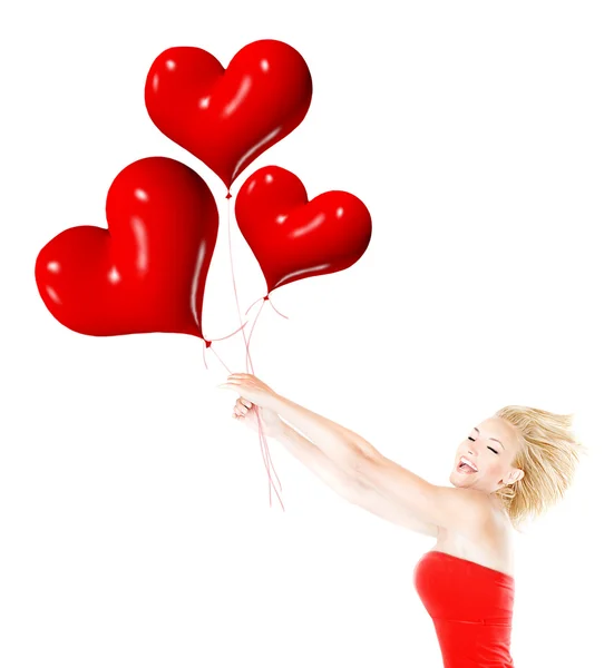 Menina feliz voando, segurando balões de coração vermelho — Fotografia de Stock
