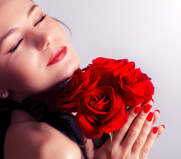 Beautiful female holding red roses bouquet, valentine romantic rose gift, woman over pink abstract background with closed eyes, happy young girl with flowers dr
