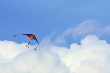 Rainbow colored kite in the clouds clipart