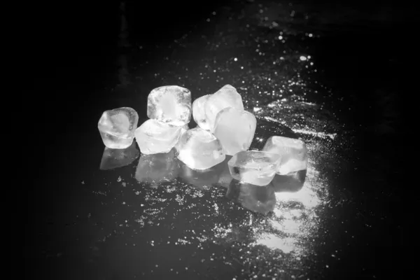 Cubos de gelo preto e branco em água gelada — Fotografia de Stock